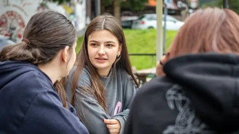 Tre unga kvinnor samtalar vid utomhusbord