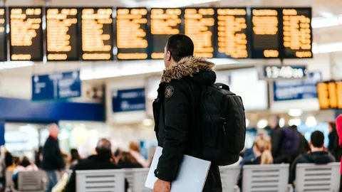 Resenär framför avgångstavla på flygplats